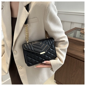 Détail du sac bandoulière noir matelassé avec chaîne dorée et boucle métallique