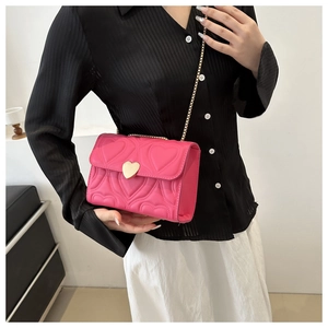 Detail of rose red heart-quilted crossbody bag with gold heart clasp and chain strap