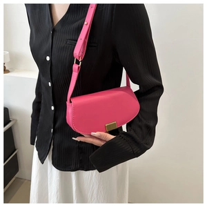 Detail of magenta saddle bag with gold metal buckle and adjustable leather strap