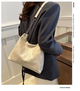 Detail of cream PU leather tote bag with silver metal chain strap and logo