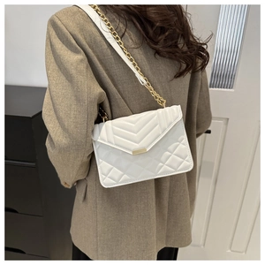 Detail of white quilted crossbody bag with golden chain strap and textured leather finish