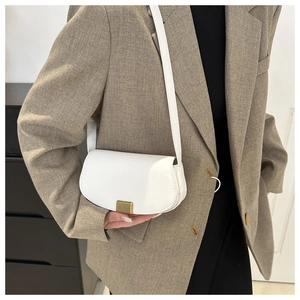 Close-up of white leather crescent saddle bag featuring a textured gold metallic buckle