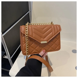 Détail du sac matelassé marron caramel avec chaîne dorée et coutures en forme de V