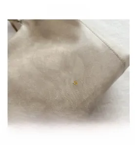 Dettaglio della borsa in pelle PU beige che mostra la trama fine e la scritta dorata