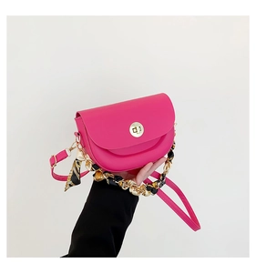 Detail of rose pink saddle bag with golden clasp and decorative scarf handle chain