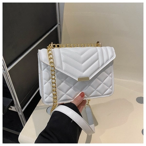 Détail d'un sac à bandoulière blanc matelassé avec chaîne dorée et fermoir en métal