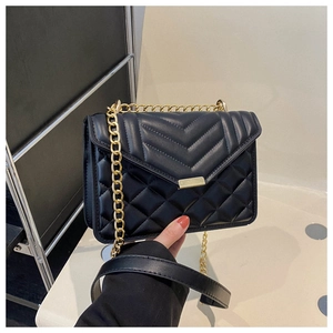 Détail d'un sac à bandoulière matelassé noir avec coutures en V et chaîne dorée