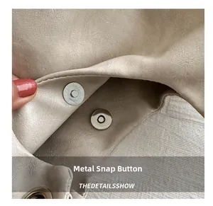 Dettaglio macro della chiusura magnetica su borsa tote beige in pelle testurizzata