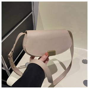 Detail of beige saddle bag showing smooth texture and vertical gold metal clasp closure