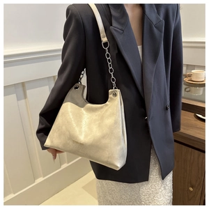Sac à épaule chic en similicuir beige avec fini métallisé et chaîne sur un mannequin