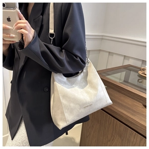 Dettaglio della borsa a spalla in ecopelle bianco crema con scritte dorate e tracolla a catena