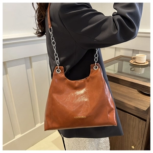 Detail of a brown leather shoulder bag with thick silver chain and fashion text logo