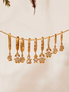 Detailed view of 18k gold-plated heart earrings with zircon cartoon pendants on beige fabric