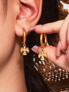 Nahaufnahme eines goldenen Engelsflügel-Ohrrings mit Zirkonia-Kristallen und Matt-Finish
