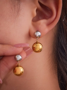 Close-up of minimalist hollow steel bead earrings in two-tone gold and silver finish