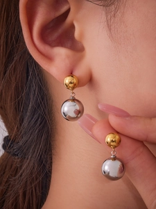 Close-up of mixed metal spherical drop earrings in gold and silver on a model