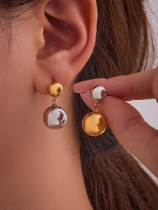 Detail of two-tone stainless steel ball drop earrings in 18k gold and silver finish