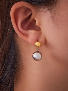 Detail of two-tone hollow steel ball drop earrings worn with 18k gold and silver mirror finish