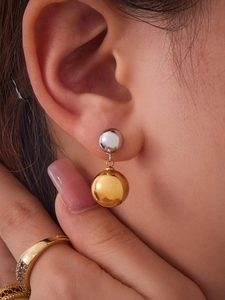 Close-up of two-tone stainless steel ball drop earrings featuring gold and silver spheres