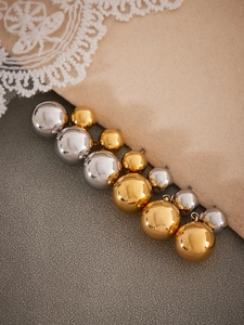 Detailed view of mirror-polished gold and silver ball stud earrings in various sizes