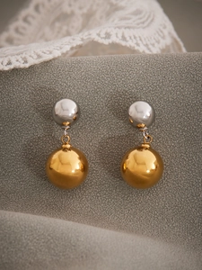 Close-up of hollow mixed-metal earrings with silver and 18k gold-plated steel spheres