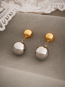 Detailed view of dual-tone hollow steel earrings with gold and silver spheres