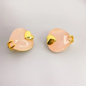 Makro-Detail von 18K vergoldeten Herzohrringen mit rosa Edelsteinen und kleinen Goldherzen