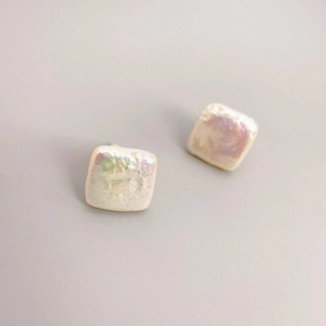Baroque square pearl stud earrings with rainbow luster on a minimalist grey background