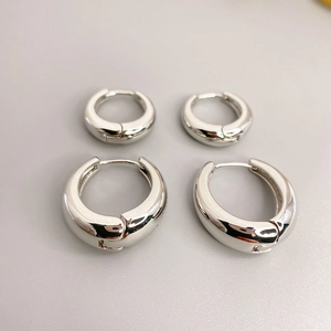 Minimalist silver metal huggie hoop earrings with polished mirror finish in two sizes