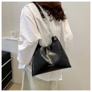 Dettaglio della borsa hobo in pelle lucida nera con catena d'argento su un modello