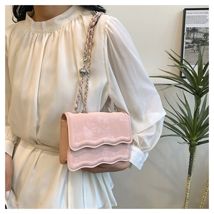 Detail of pink velvet crossbody bag with scalloped flap and silver metal chain strap