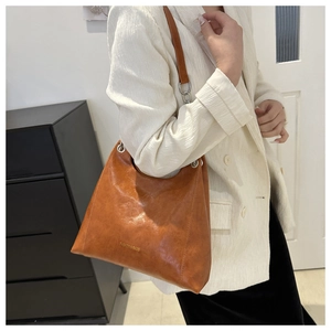 Détail du sac bandoulière en similicuir marron avec logo Fashion & Bags et texture vintage