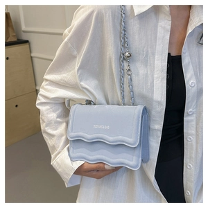 Close-up of light blue crossbody bag featuring a unique wave-edge flap and silver chain