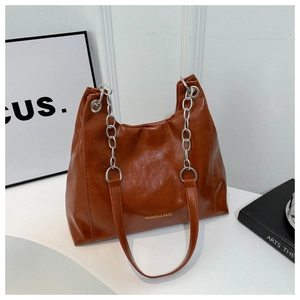 Close-up of brown glossy PU leather tote bag with silver chain strap and fashion logo