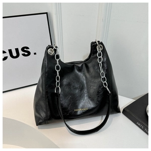 Detail of black PU leather shoulder bag with gold logo and silver chain strap