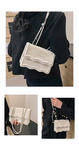 Detail of cream square bag with scalloped flap edge and silver adjustable ball chain strap
