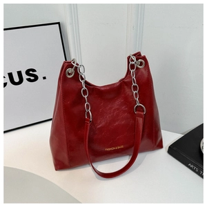 Detail of dark red faux leather tote bag with silver chain strap and gold logo text