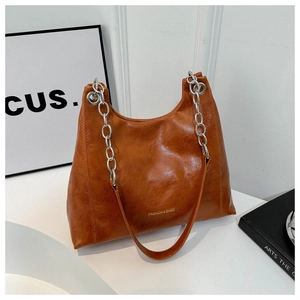 Detail of caramel brown faux leather shoulder bag with gold logo and silver chain strap