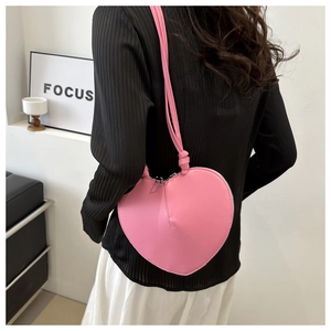 Detail showing pink heart-shaped crossbody bag with smooth PU leather and knot strap