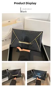 Detail of black crocodile pattern envelope clutch bag with gold V-shape metal trim