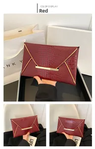 Detail of red envelope clutch featuring crocodile pattern and gold metal fastener