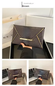 Detail of a brown crocodile pattern envelope clutch featuring elegant gold metal trim