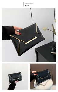 Close-up of black crocodile pattern envelope clutch with gold metal trim and buckle