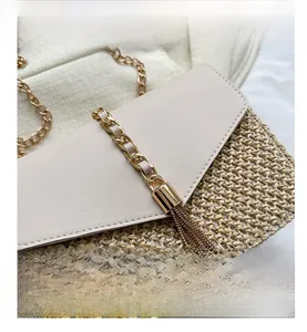 Detail of woven straw bag featuring gold tassel charm and leather chain shoulder strap
