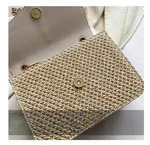 Detail of golden magnetic clasp on a woven straw bag with beige textured finish