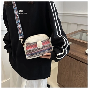 Détail d'un sac bandoulière en toile avec motifs tissés colorés et large sangle