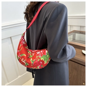 Detailansicht einer roten Umhängetasche mit Blumenmuster und verstellbarem Schultergurt