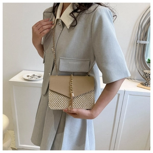 Detailed shot of straw woven crossbody bag with leather flap and gold chain fringe