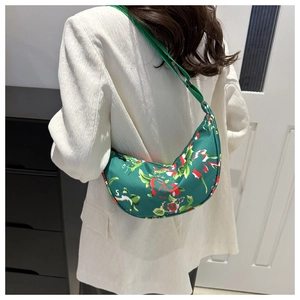 Detail der grünen Hobo-Tasche mit Blumenmuster an der Schulter über einem Blazer