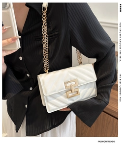 Close-up of V-quilted white crossbody bag featuring golden geometric chain and lock